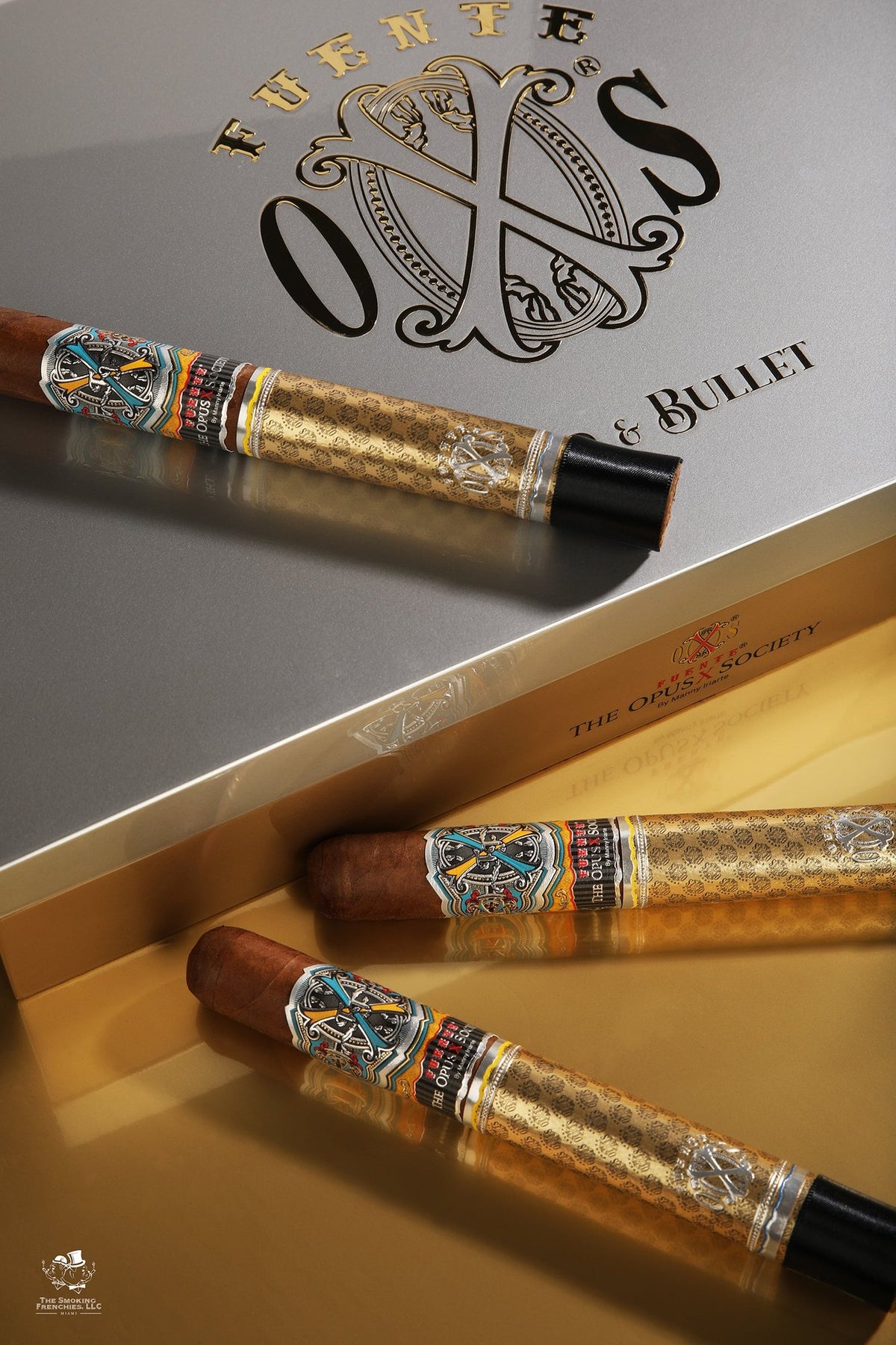Three Fuente Fuente OpusX Gold & Bullet cigars in gold sleeves on the silver Gold & Bullet box lid
