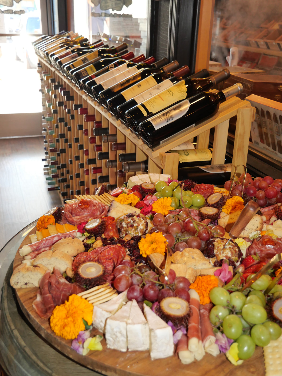 Charcuterie board beneath a display of wine bottles at Sun of a Gun Cigars & Spirits, Yuma, Arizona