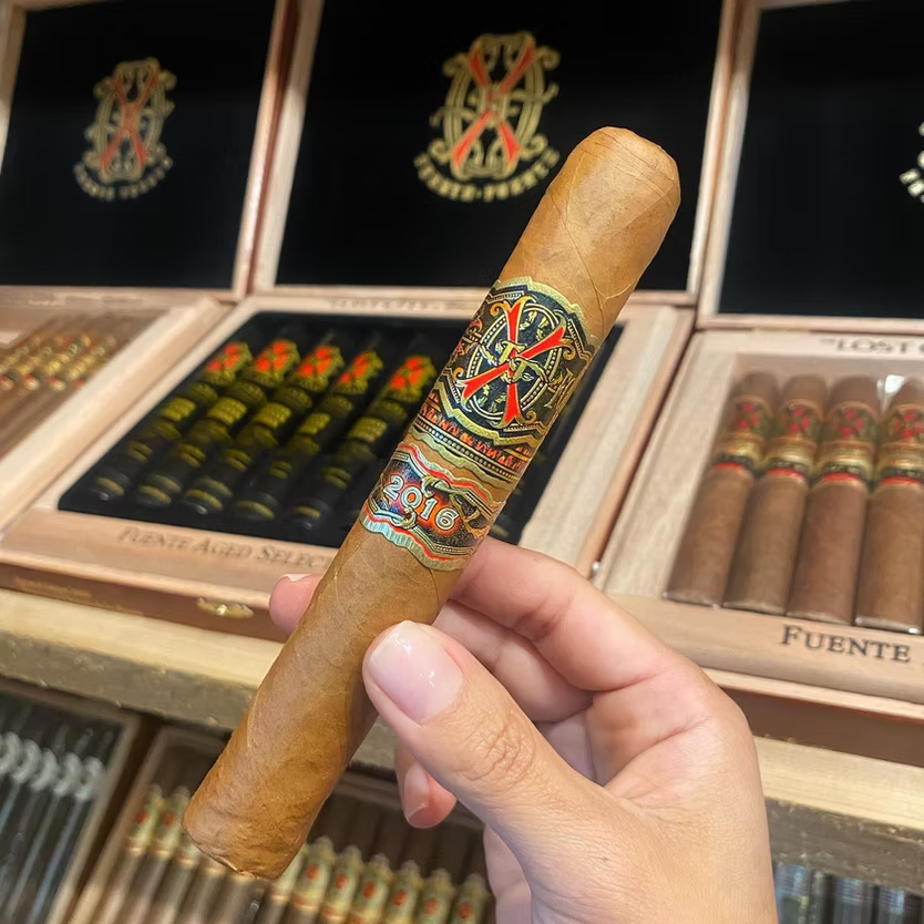Arturo Fuente Opus X cigar held above Fuente boxes in the humidor at Sun of a Gun Cigars & Spirits, Yuma, Arizona
